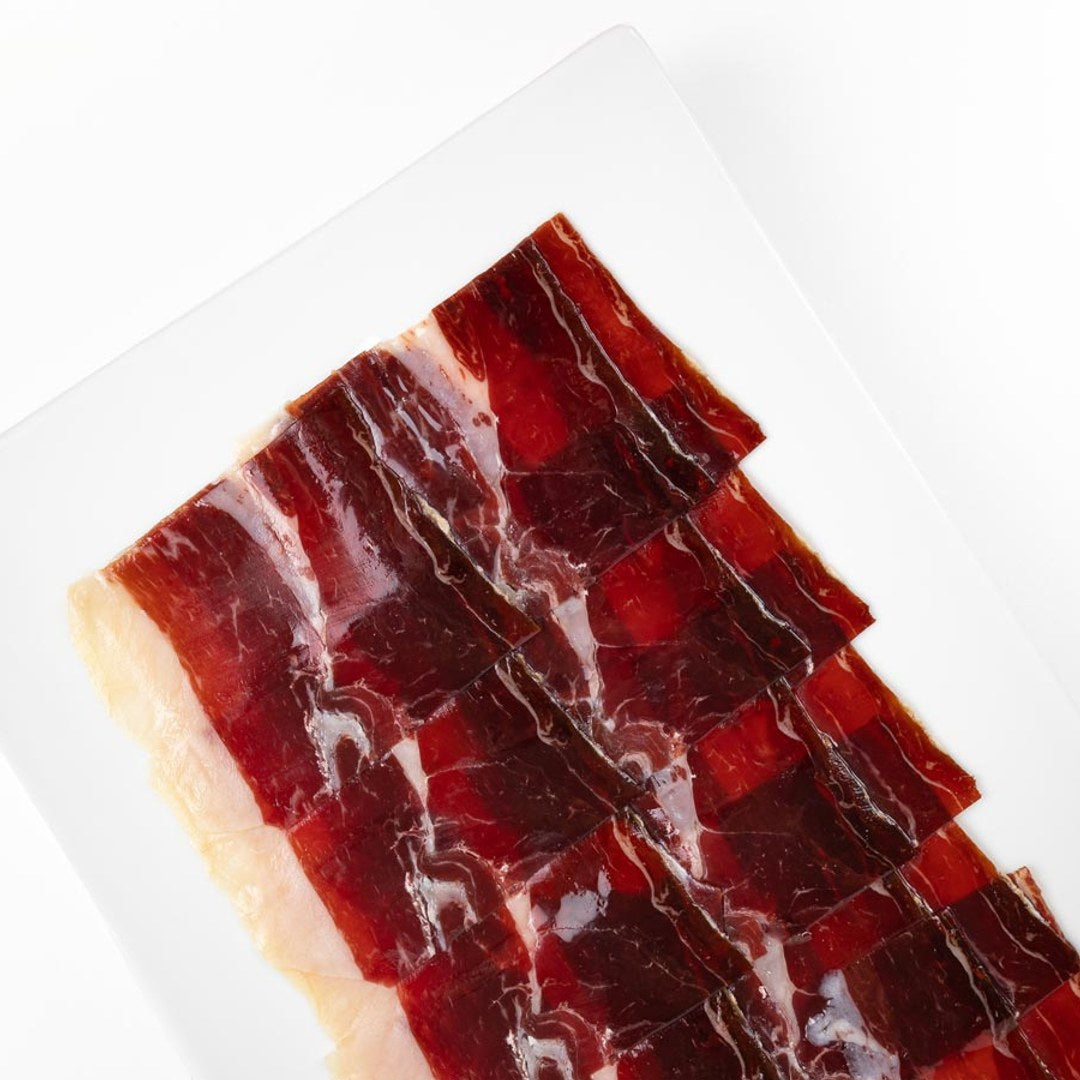 Lonchas de jamón ibérico cortadas a cuchillo en una bandeja blanca