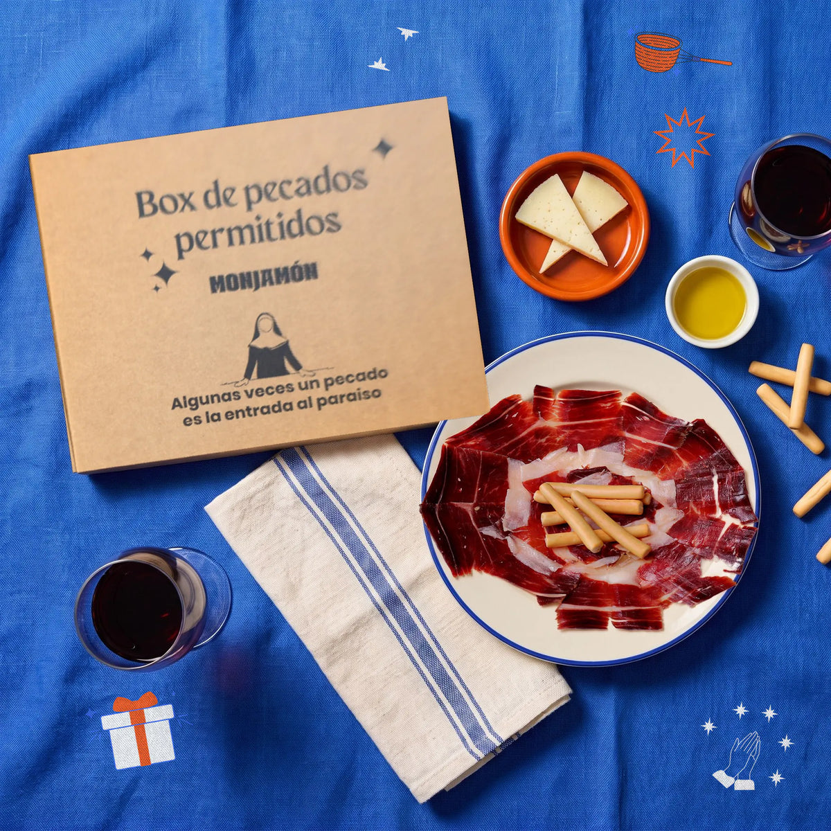 Cesta Caída del Cielo con Jamón de Bellota 100% Ibérico – vista desde arriba: la caja de la cesta junto a un plato de jamón, queso, aceite y dos copas de vino