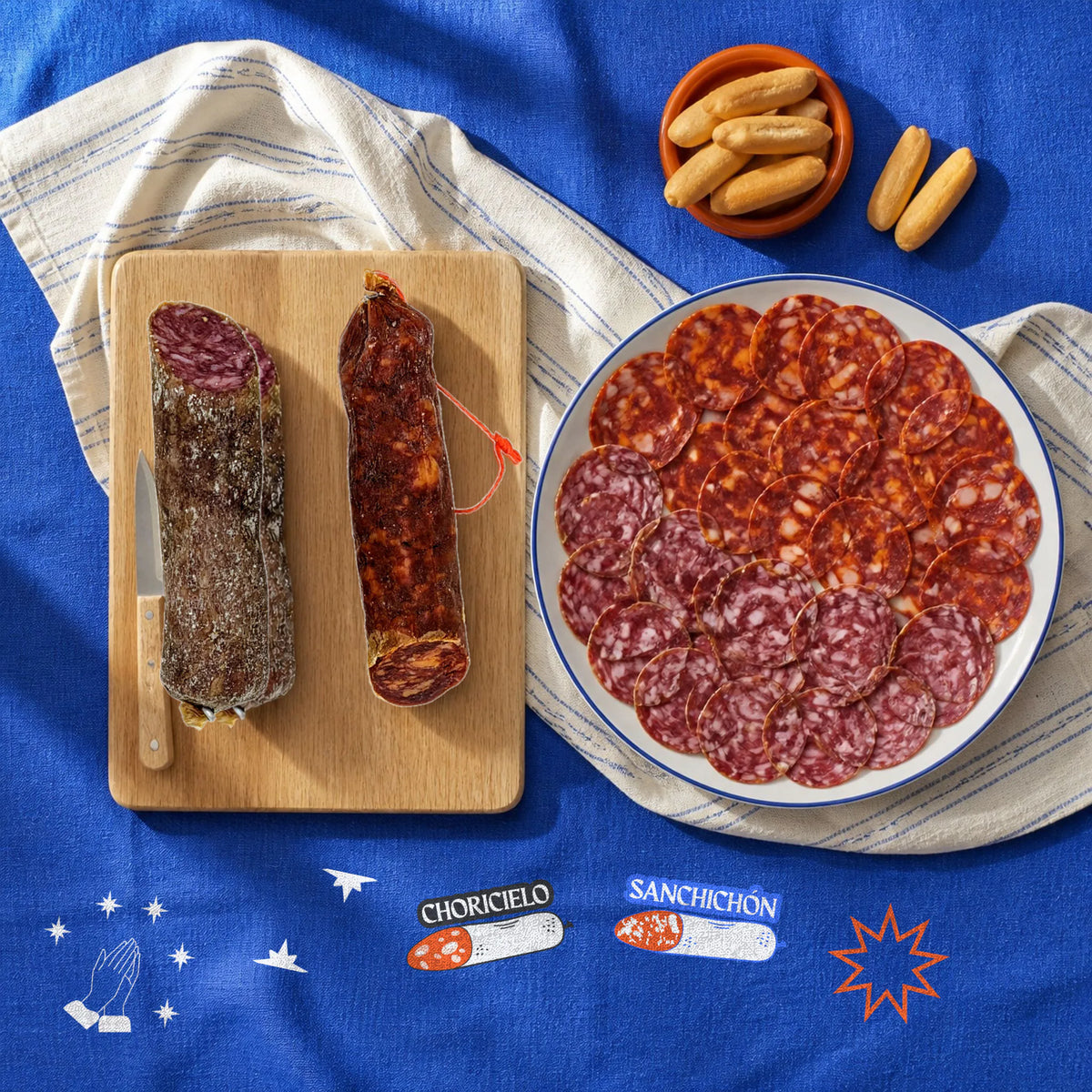 Vela ibérica [Estilo FUET] – vista desde arriba: las velas ibéricas en su tablita junto a un plato recién cortado