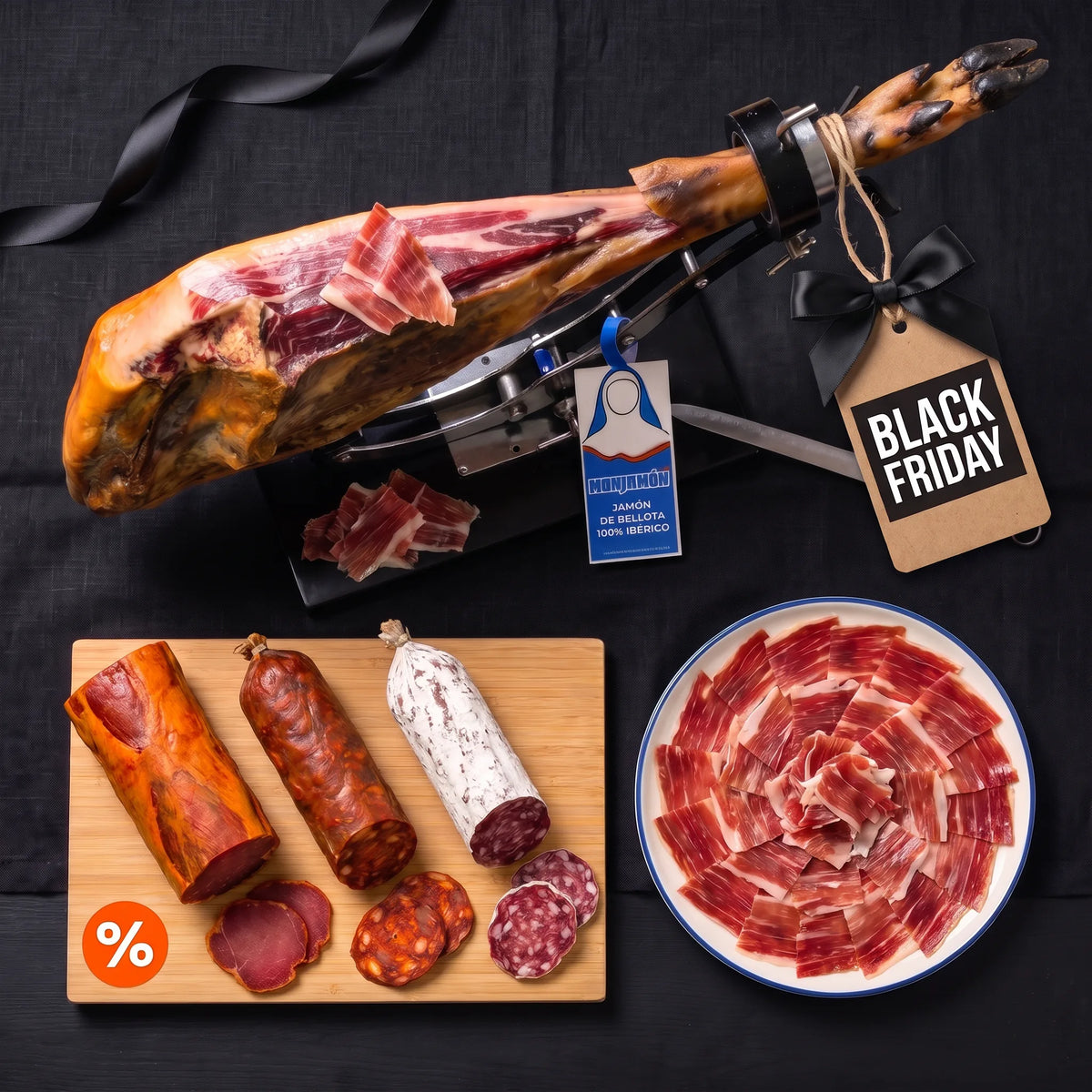 Pack Pecado Carnal · Black Friday – vista desde arriba: jamón de bellota 100 % ibérico +42 meses entero sobre un jamonero, medias piezas de Lomonasterio, Choricielo y San Chichón, y un plato de jamón