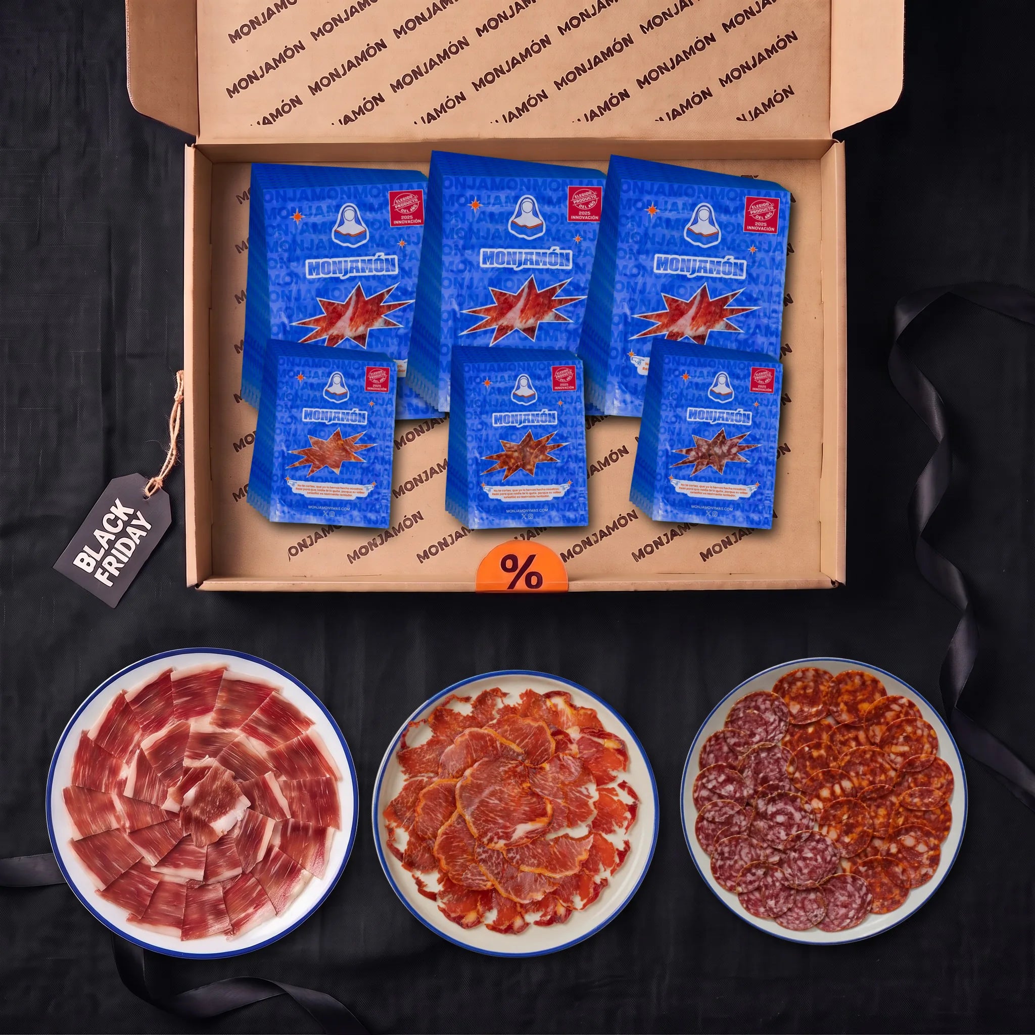 Pack Pecado Carnal Loncheado · Black Friday – vista desde arriba: la caja con el jamón de bellota 100 % ibérico +42 meses loncheado en 30 sobres y 24 sobres de Lomonasterio, Choricielo y San Chichón, con un plato de jamón, otro de lomo y otro de chorizo y salchichón