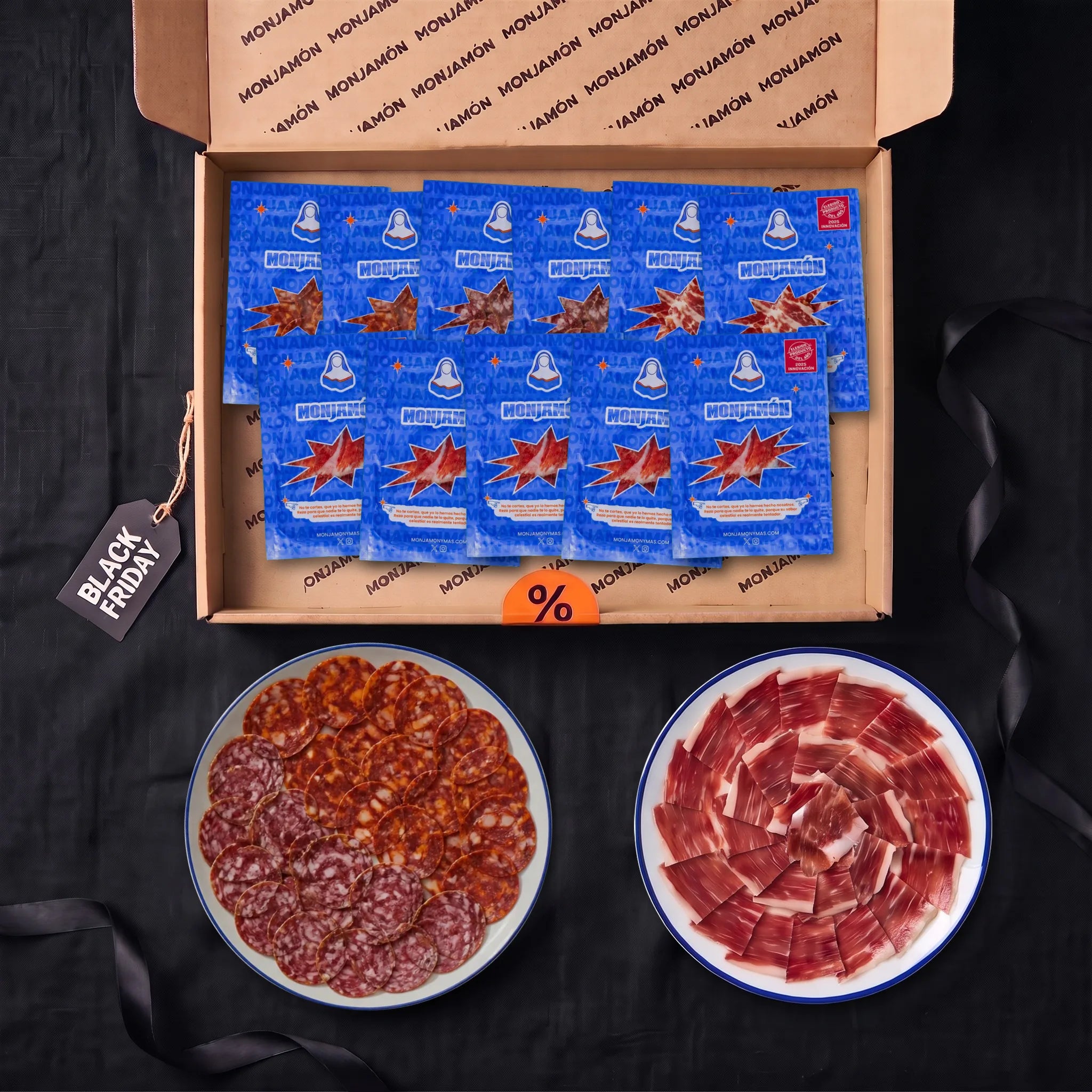 Pack Tentación · Black Friday – vista desde arriba: la caja con 5 sobres de jamón de bellota 100 % ibérico +42 meses y 6 sobres de embutido (2 de Choricielo, 2 de San Chichón y 2 de Divina Coppa), con un plato de chorizo y salchichón y otro de jamón