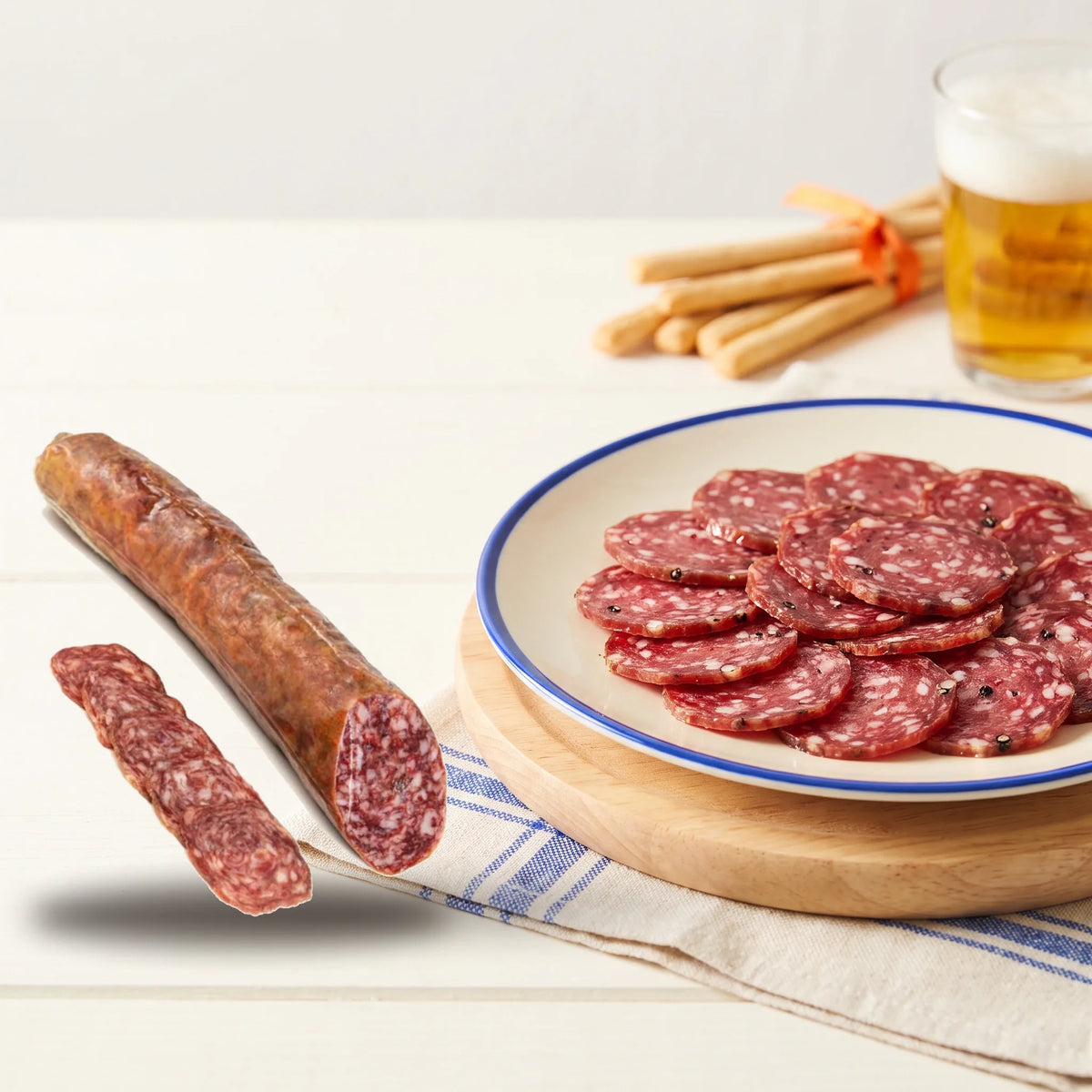 San chichón · Salchichón de Bellota 100% Ibérico · Media pieza 450-500 g – la pieza junto a un plato de San Chichón recién cortado